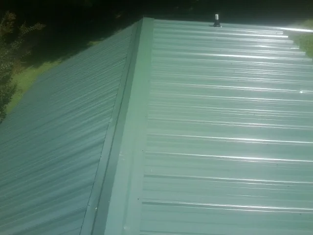New green metal panels meeting at the ridge of a roof — Flat Roof Repair work by our crew in Bumpus Mills