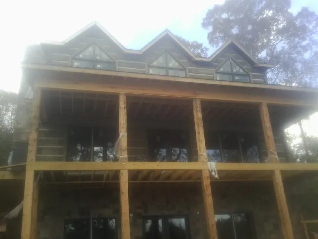 Dormers and porch framing on a large log home under construction — Roof Coating work by our crew in Bumpus Mills