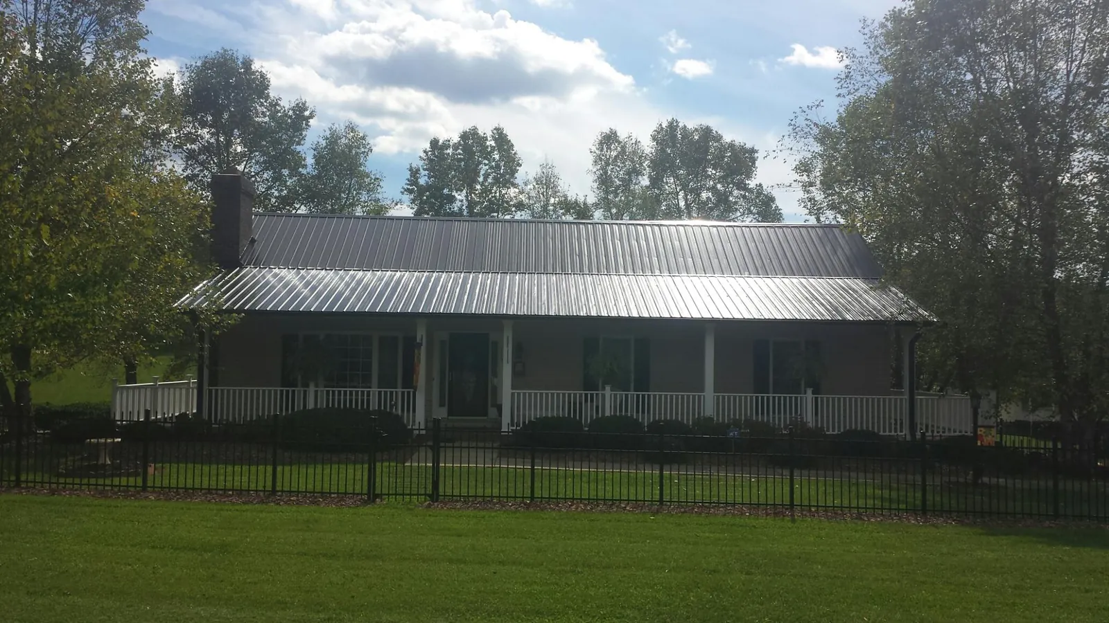 Gray metal roof on a brick ranch with a full width front porch — Gutter Guard Installation work by our crew in Bumpus Mills