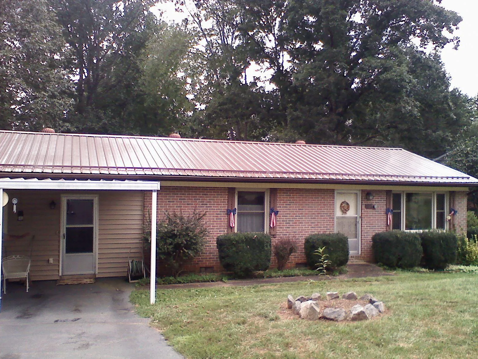 Bronze metal roof and carport on a brick ranch home — Roof Repair work by our crew in Bumpus Mills