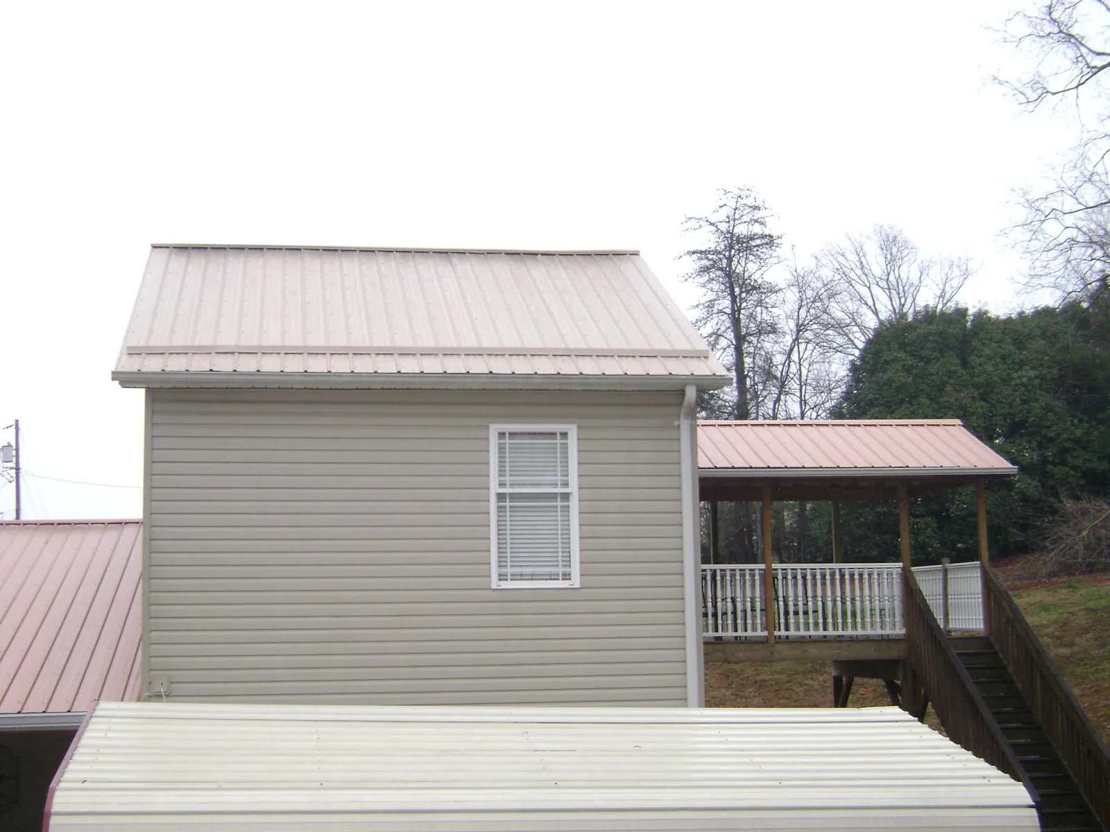 Tan metal roofs on a two story addition and attached porch, from a Roof Replacement job in Bumpus Mills