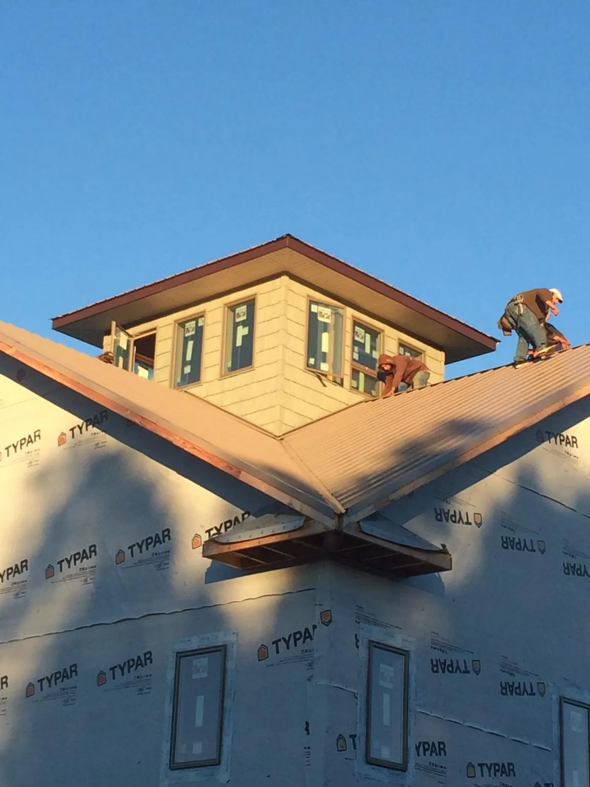 Roofers working around a rooftop cupola on a new metal roof at sunset — Roof Waterproofing in Bumpus Mills by Roofing Brothers